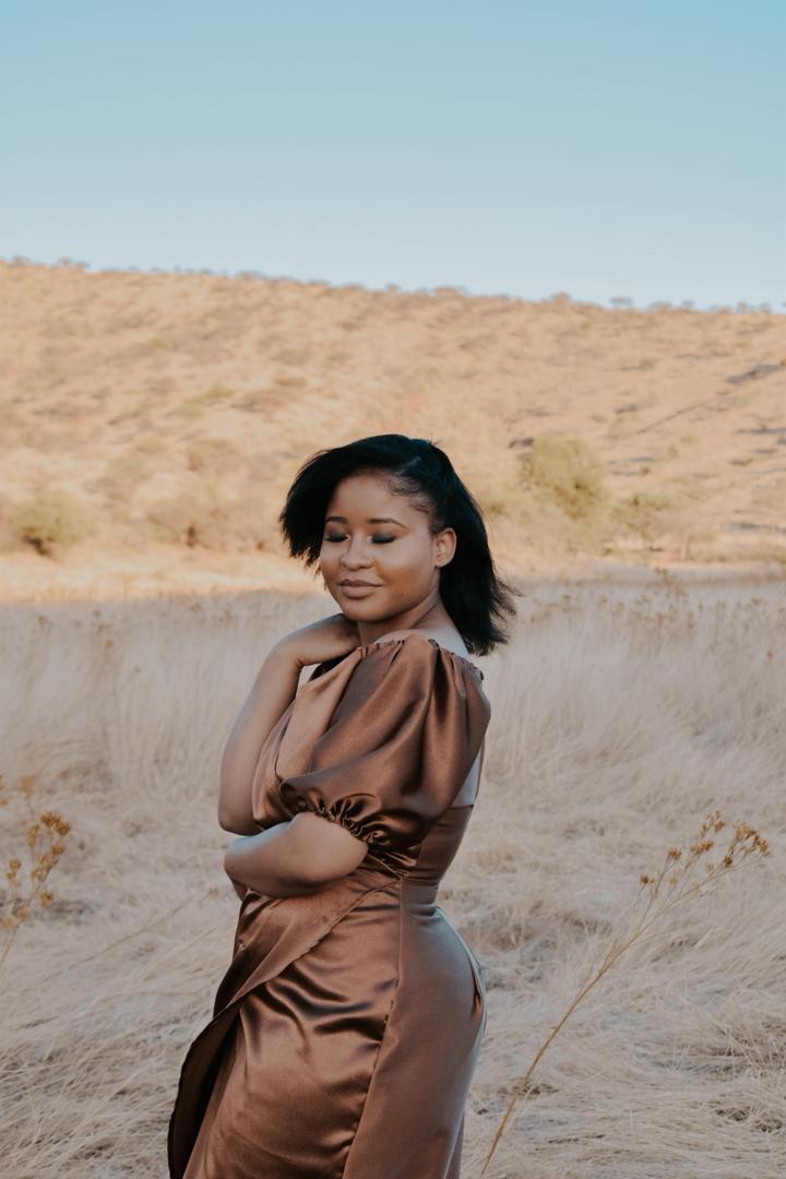A silhouette of a woman standing in a sunset-lit landscape