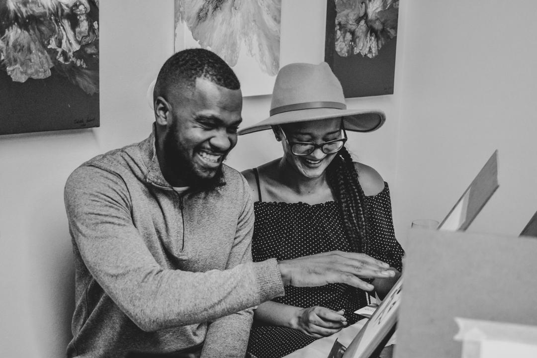 An intimate photo of a couple holding hands in a field at sunset